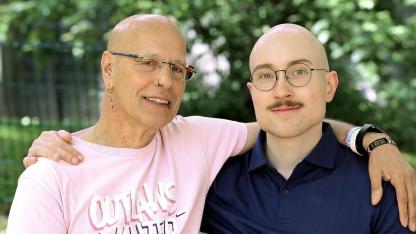 Die beiden Interviewten stehen Arm in Arm in einem sonnigen Park.